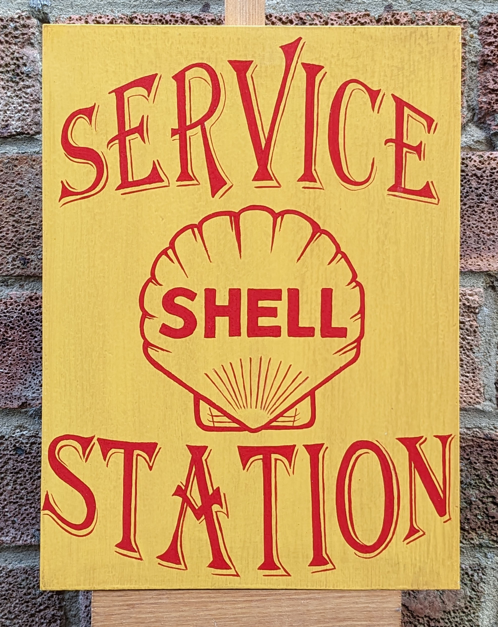 Signwritten 'Shell Service Station' hand painted sign, yellow panel red lettering.